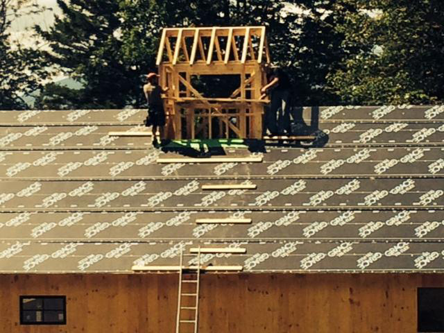 Employees working on a timber frame barn roof