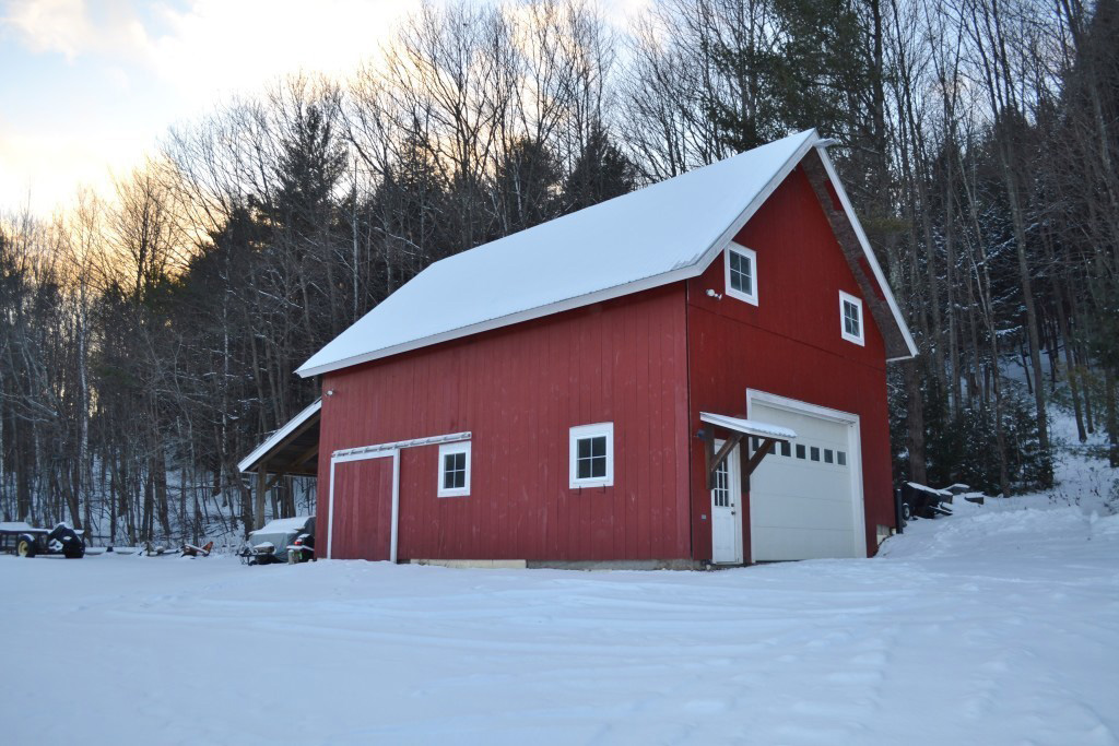 Finished exterior of a red timber frame barn in the winter