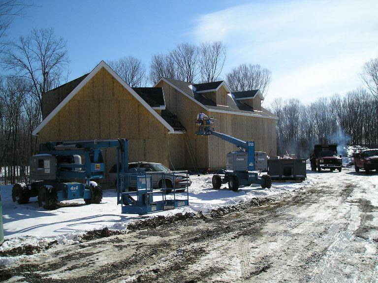Timber frame structure of a colonial with construction vehicles surrounding it