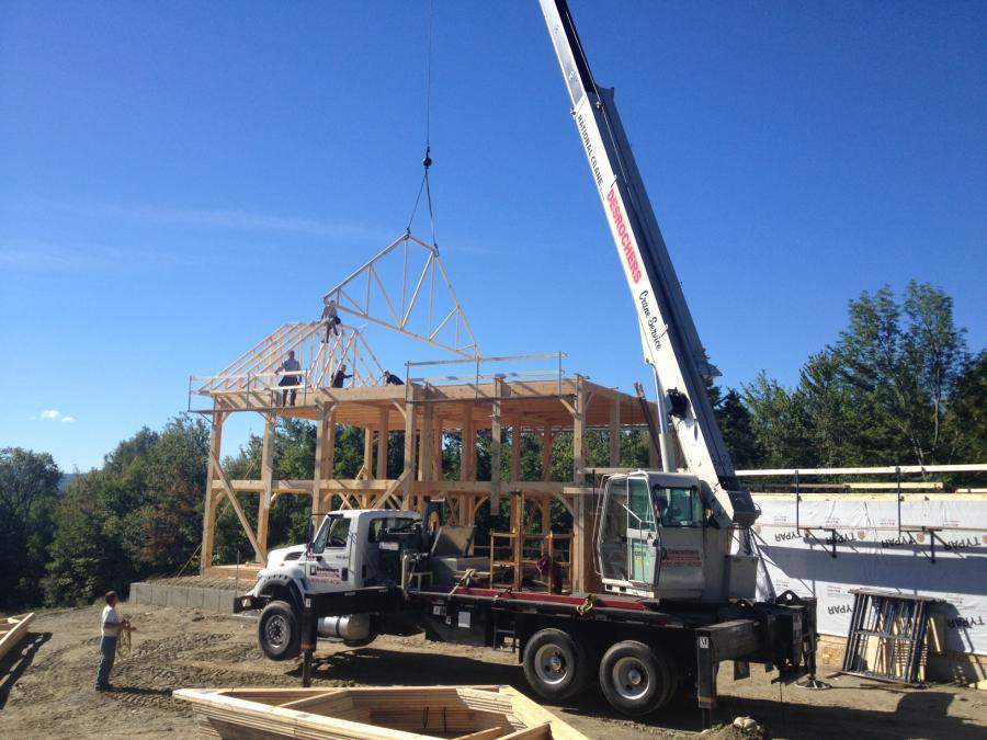 A crane bringing a truss to the top of the colonial frame structure