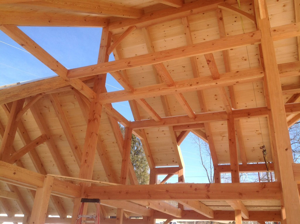 Timber frame dutch saltbox structure with wood panels covering the roof