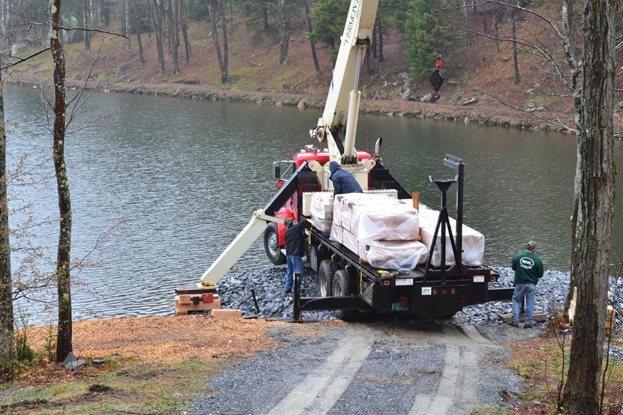 Unloading timber with the crane by the edge of the lake