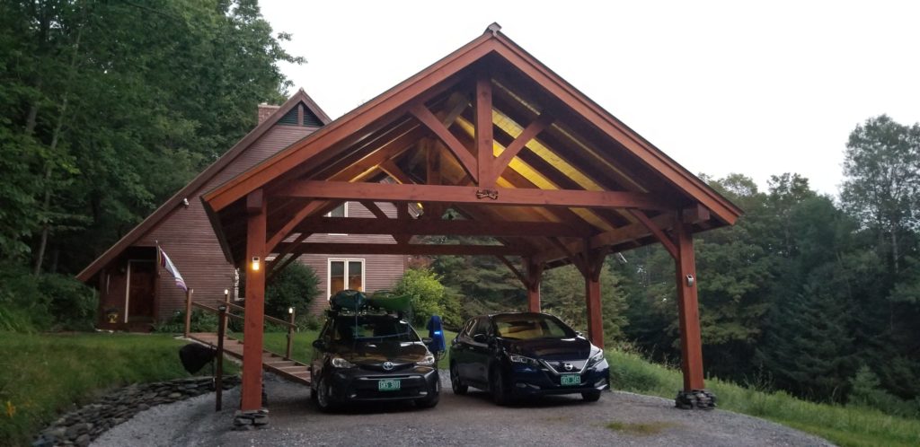 Finished timber frame car port with two vehicles underneath.