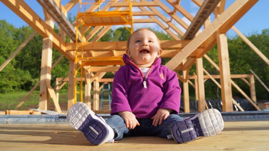 Baby sitting in front of a timber frame structure