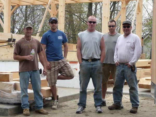 Crew in front of timber frame colonial structure