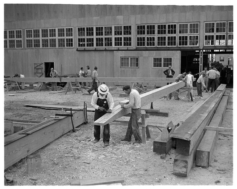 Timber framers working on a frame in lumber yard
