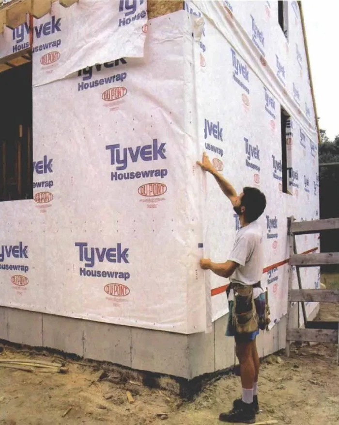 Image of carpenter sealing up a house wrap